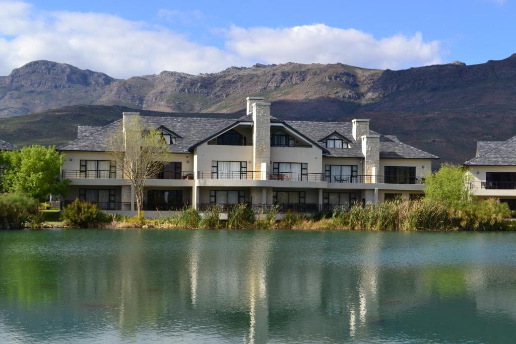 a building with mountains in the background next to a lake at Pearl Valley-Golf Safari SA in Paarl