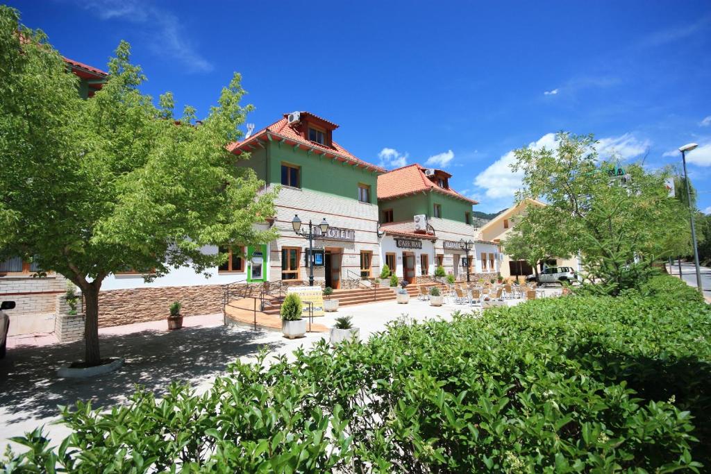 a building in a town with trees and bushes at Hotel Rural Montaña de Cazorla in Arroyo Frio