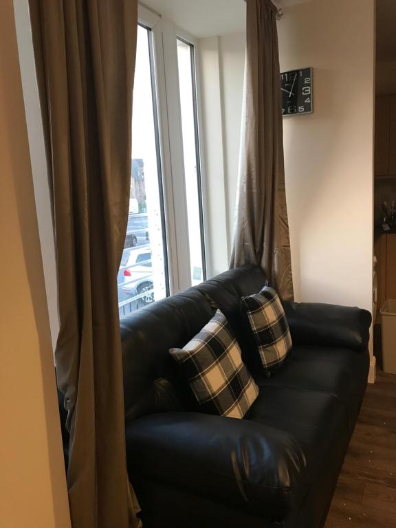 a black leather couch sitting in front of a window at River Ness Apartments in Inverness