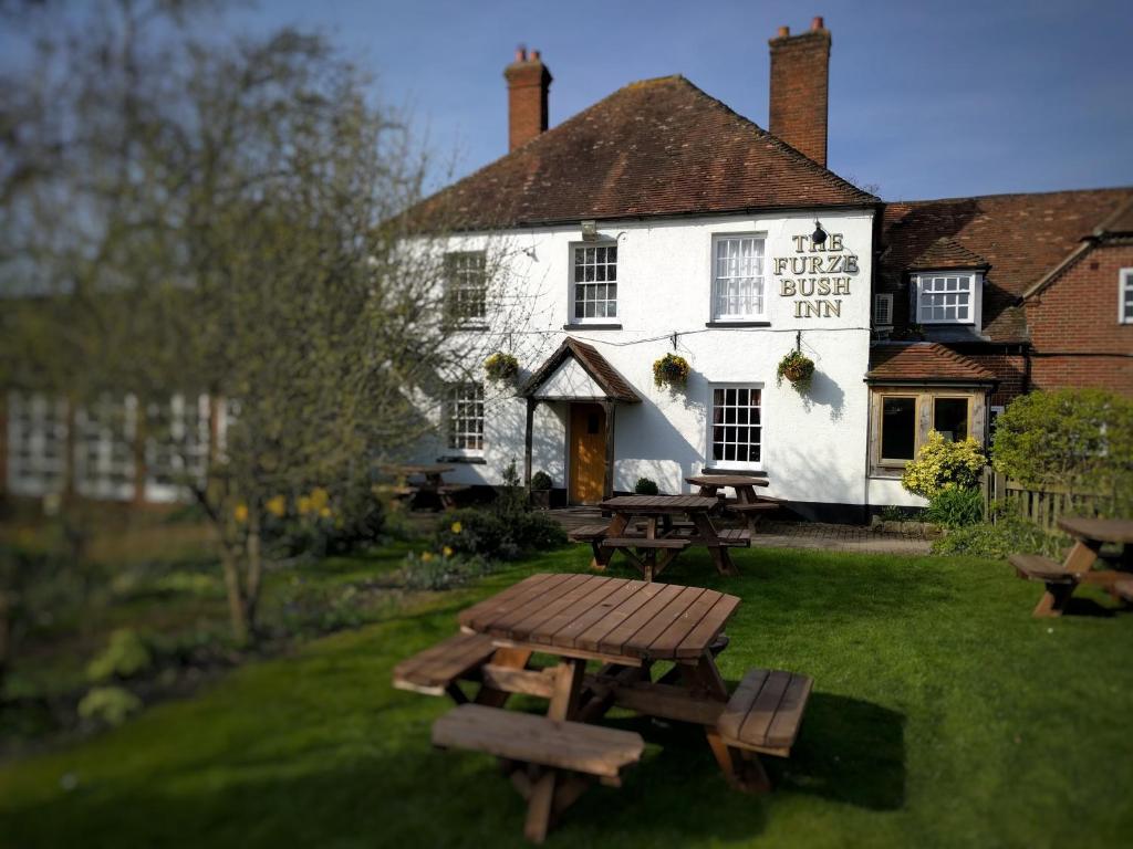 un pub con tavoli da picnic di fronte a un edificio di The Furze Bush Inn a Newbury