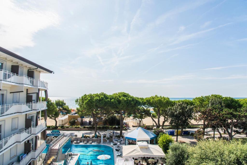 uma vista para um resort com uma piscina, mesas e guarda-sóis em Hotel Miramare em Lignano Sabbiadoro
