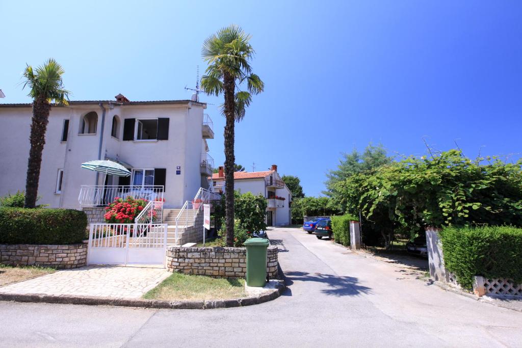 uma casa branca com palmeiras e uma rua em Apartments Laguna em Porec