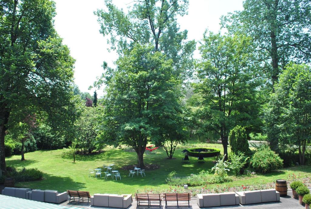 un parc avec des tables, des chaises et des arbres dans l'établissement La Roseraie. Gaume-Ardenne-lacuisine sur Semois., à Florenville