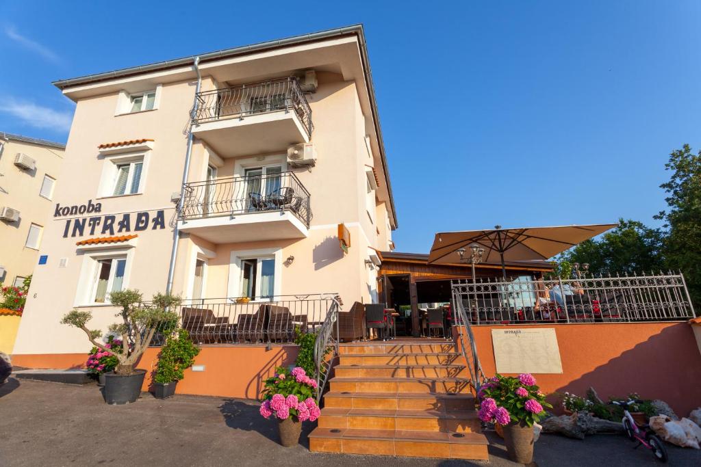 a building with stairs and flowers in front of it at Apartments Jadranka in Malinska