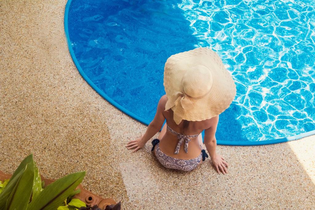 a woman in a hat sitting in a swimming pool at Villa SEAesta in Ao Nang Beach