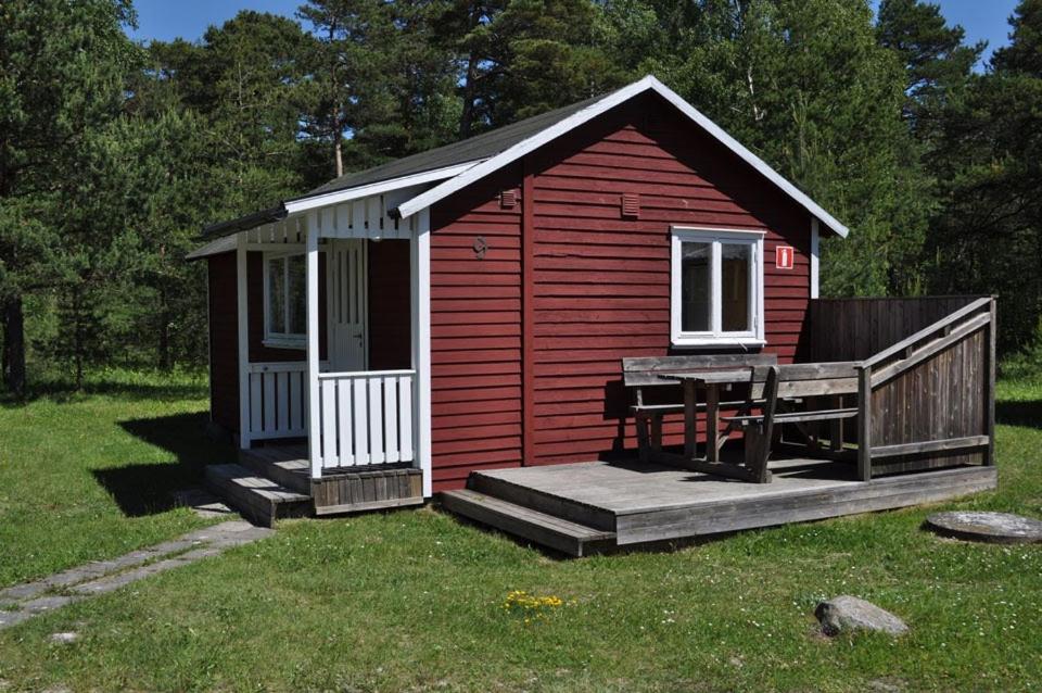 einen kleinen roten Schuppen mit einer Veranda und einer Terrasse in der Unterkunft Snäckan in Klintehamn