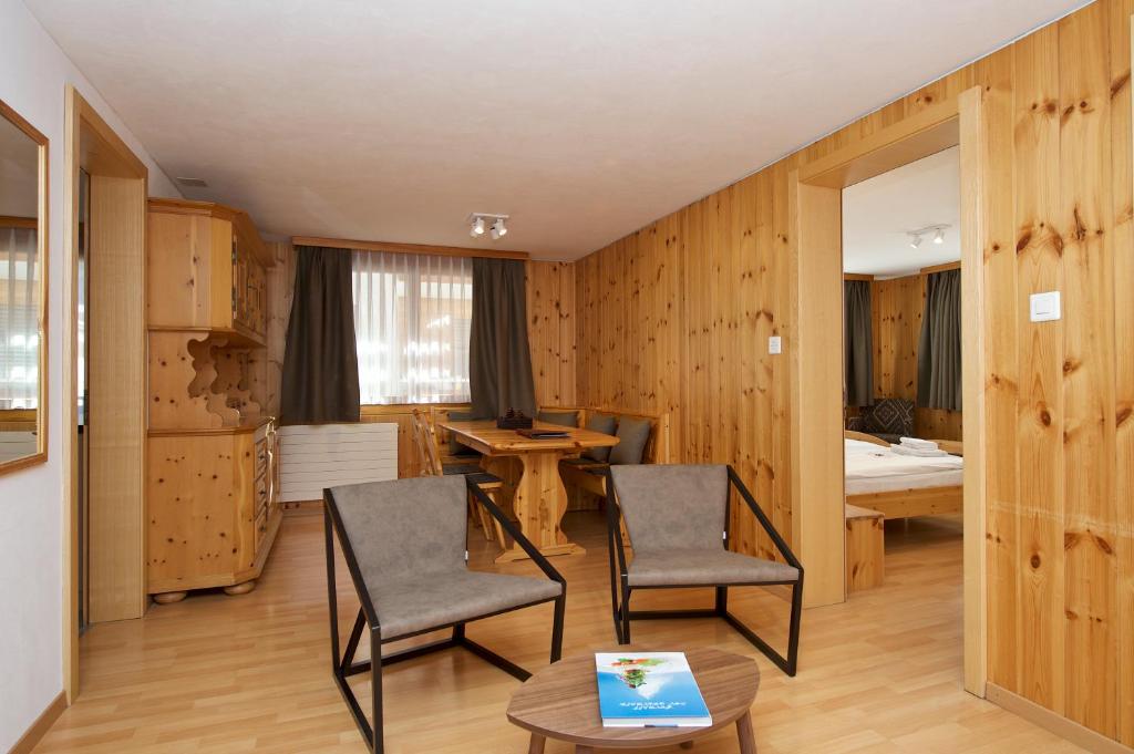 a room with chairs and a table and a bedroom at Chalet Felderhof in Zermatt