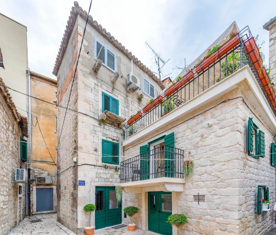 an old stone building with green shutters and a balcony at Apartments & Rooms Dujam in Split