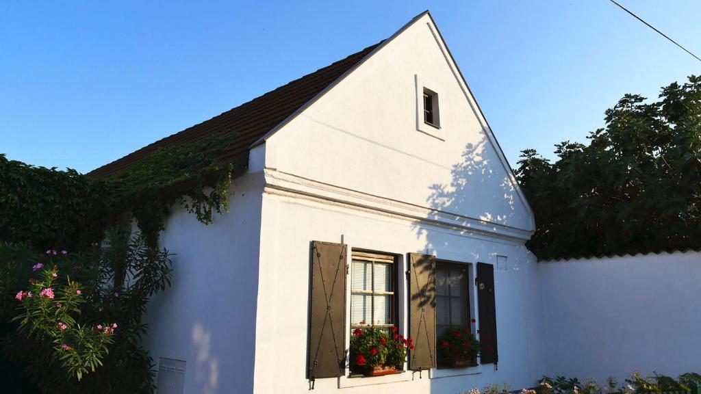 una casa bianca con fiori in una finestra di Gästehaus Doris a Purbach am Neusiedler See