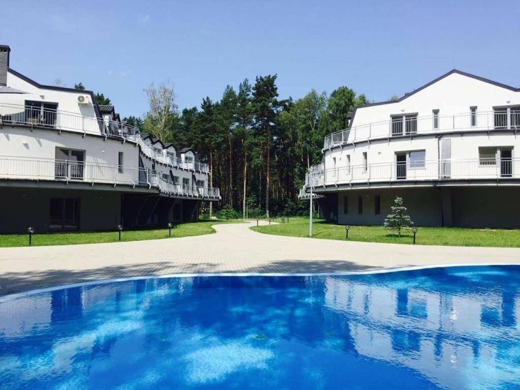 un gran edificio blanco con una piscina frente a él en Apartamenty Silence Blue Baltic, en Pobierowo