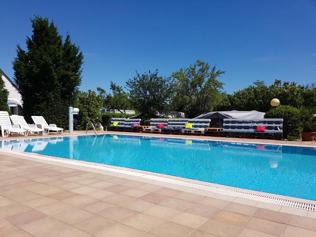 une grande piscine avec des chaises et un train en arrière-plan dans l'établissement Mandel Camping, à Paloznak