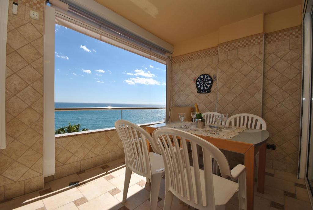 a dining room with a table and chairs and a large window at Apartamento Roca Bajondillo in Torremolinos