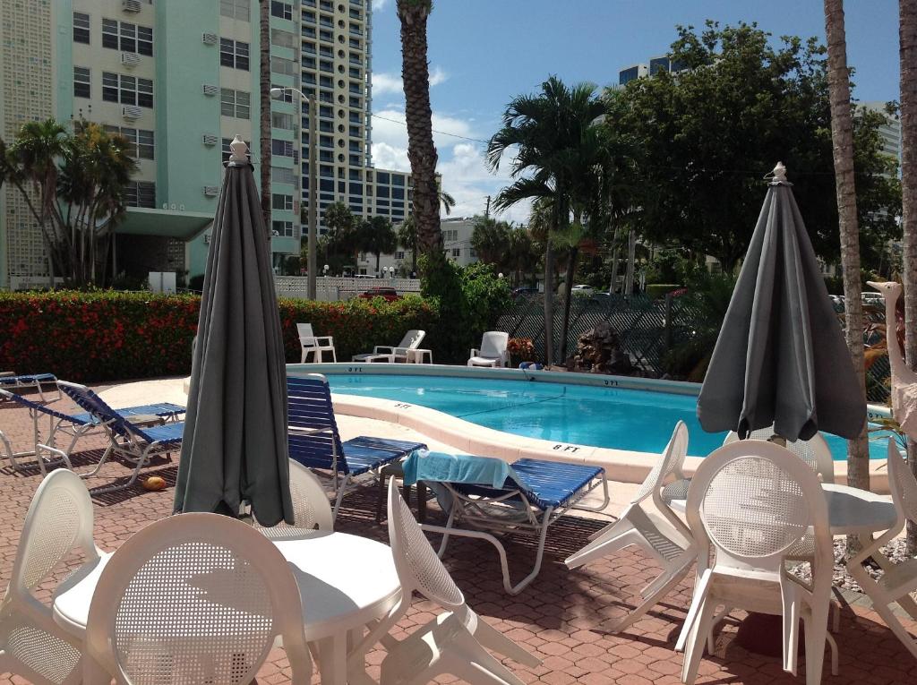 uma piscina com cadeiras, mesas e guarda-sóis em Birch Patio Motel em Fort Lauderdale