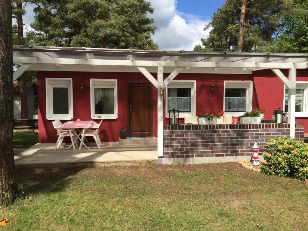 een rood huis met een tafel ervoor bij Bungalow am Schwielochsee in Schwielochsee