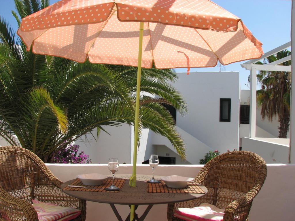 a table with two wine glasses and an umbrella at Casa Para Ti Delfinesse in Puerto del Carmen