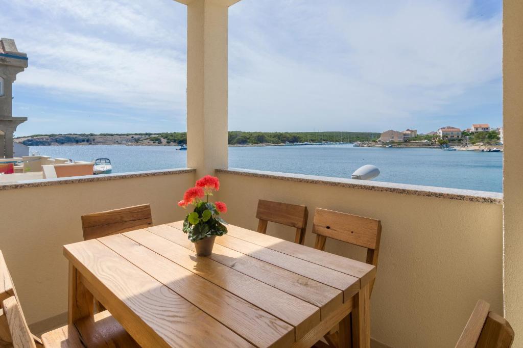 a wooden table with a vase of flowers on a balcony at Stara Kuća Apartments in Šimuni