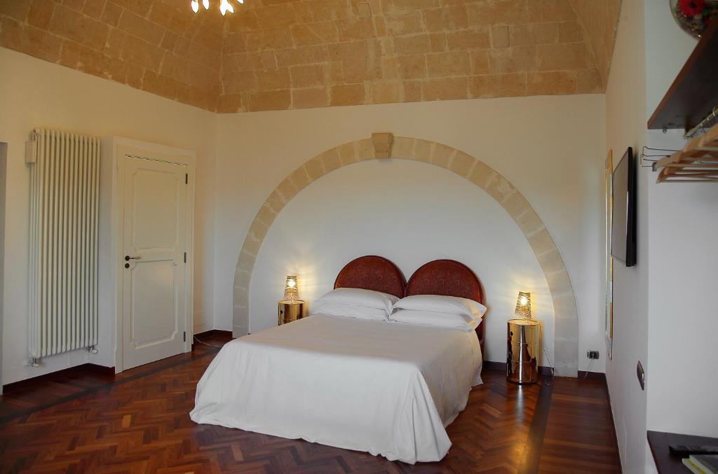 una camera da letto con un grande letto bianco con arco di Antica Civita B&B Luxury Room a Matera