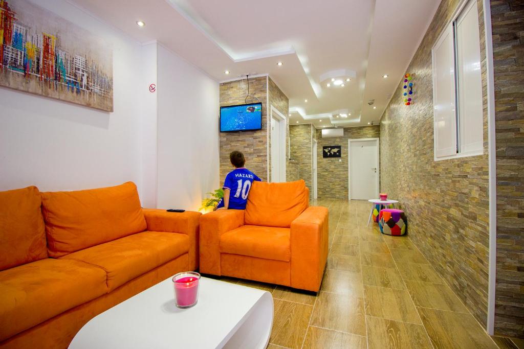a man sitting in a living room with an orange couch at Dioklecijan delux in Split