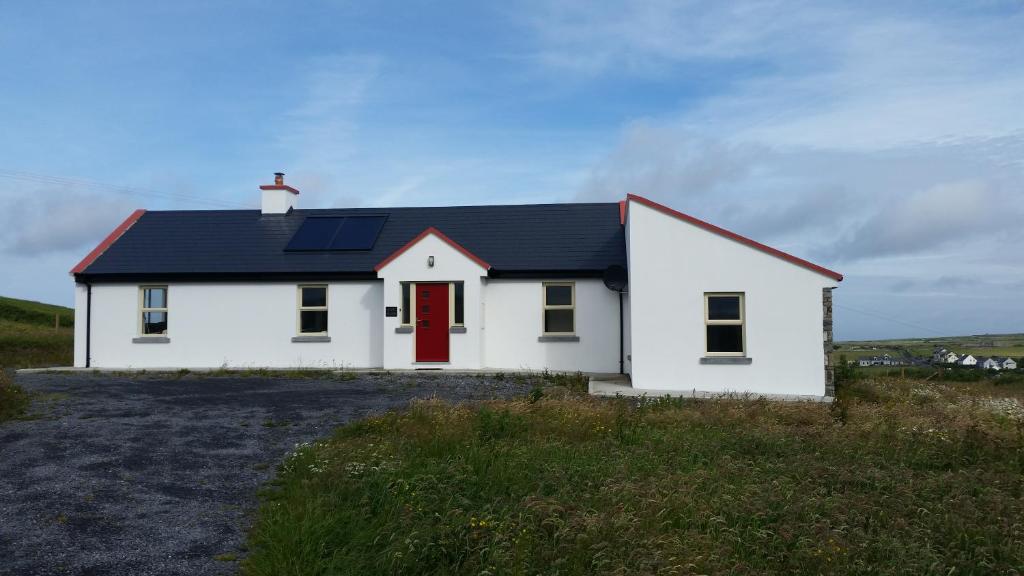 ein weißes Haus mit einer roten Tür auf einem Hügel in der Unterkunft Mary's Meadow in Doolin