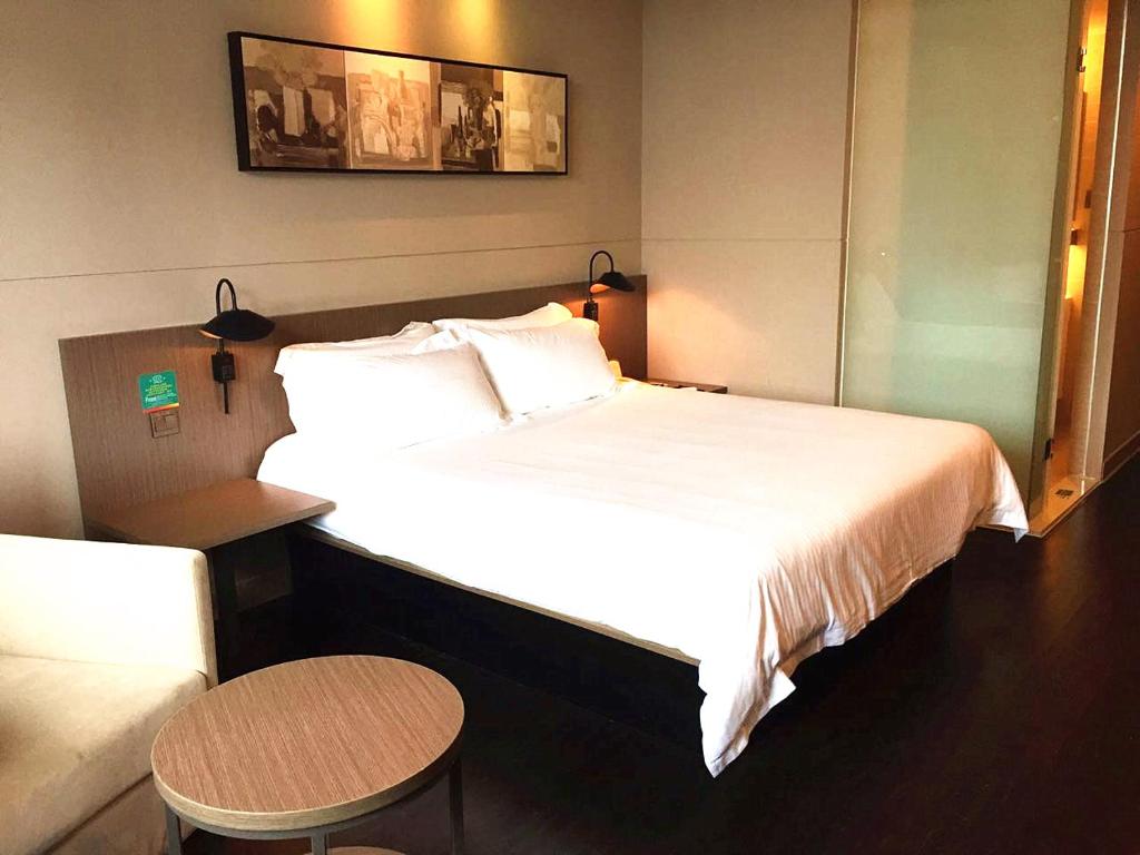 南寧市にあるJinjiang Inn Nanning Chaoyang Square People's Parkの大きなベッドとテーブルが備わるホテルルームです。