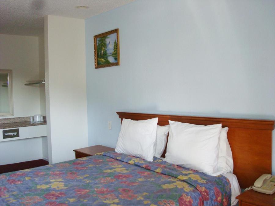 Habitación de hotel con cama y teléfono en Scottish Inns en Long Beach