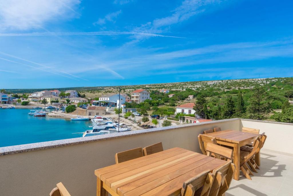 a balcony with tables and chairs and a view of the water at Stara Kuća Apartments in Šimuni