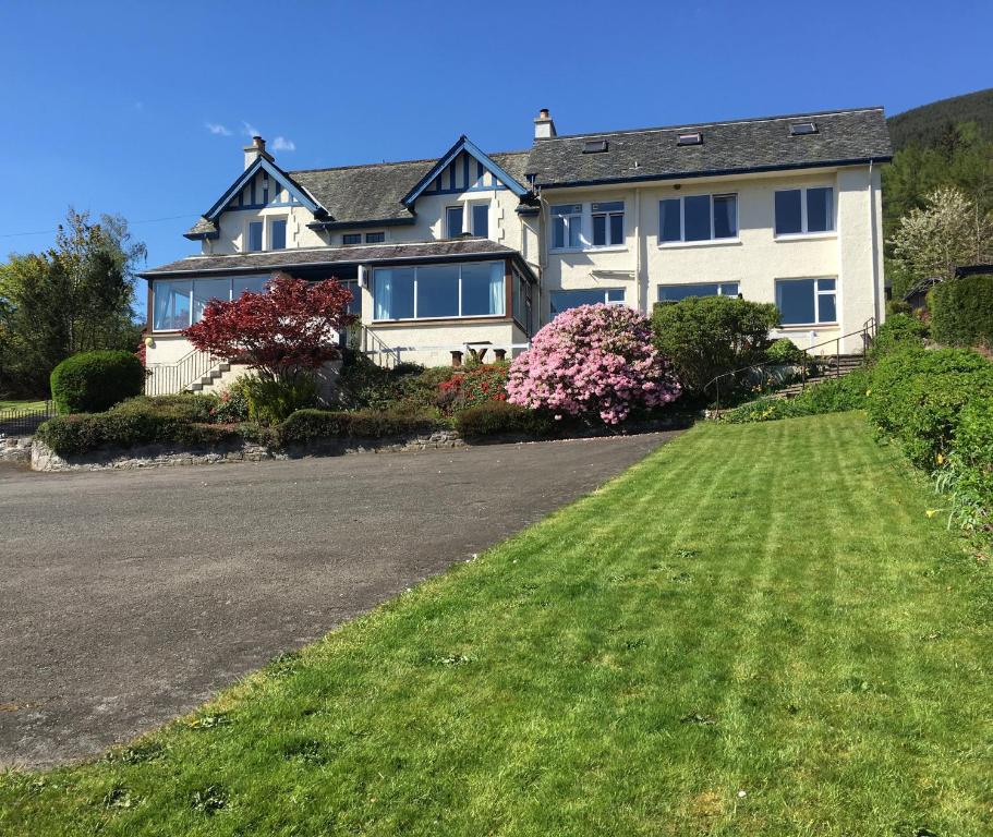 a large white house with a lawn in front of it at Lochearnhead Hotel in Lochearnhead