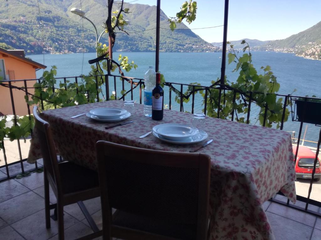 Panorama Apartment في Pognana Lario: طاولة مع أطباق وزجاجة من النبيذ عليها