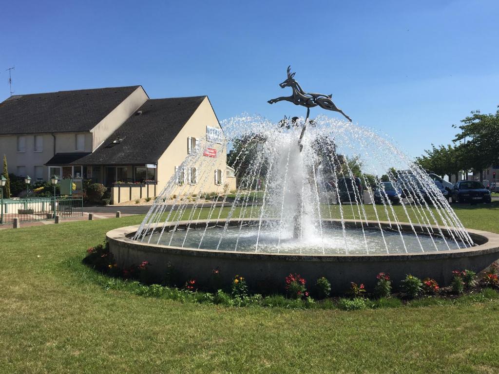 a fountain in a field with a statue in the middle at Hôtel Le Dauphin in Saint-Denis-de lʼHôtel