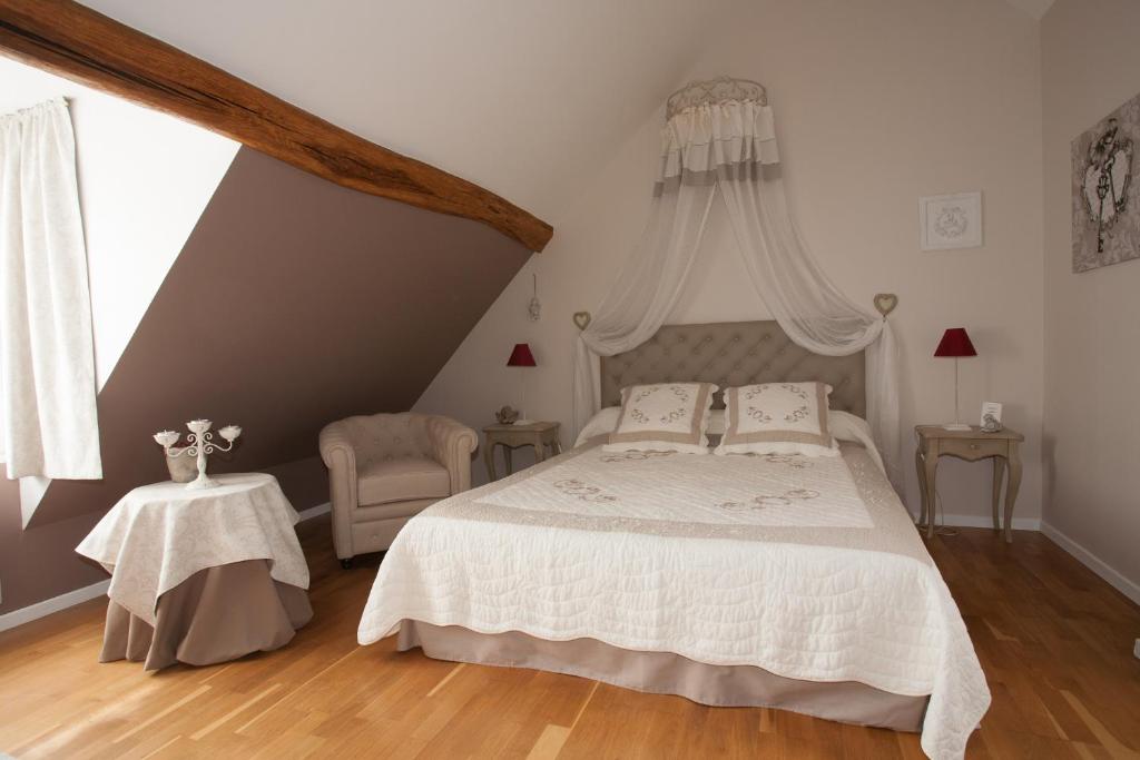 ein Schlafzimmer mit einem weißen Bett und einem Stuhl in der Unterkunft Les Jarrieres in Dame-Marie-les-Bois