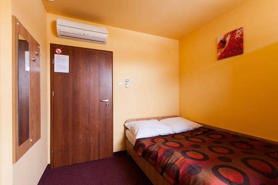 um pequeno quarto com uma cama e uma porta de madeira em Hotel Paola em Kutno