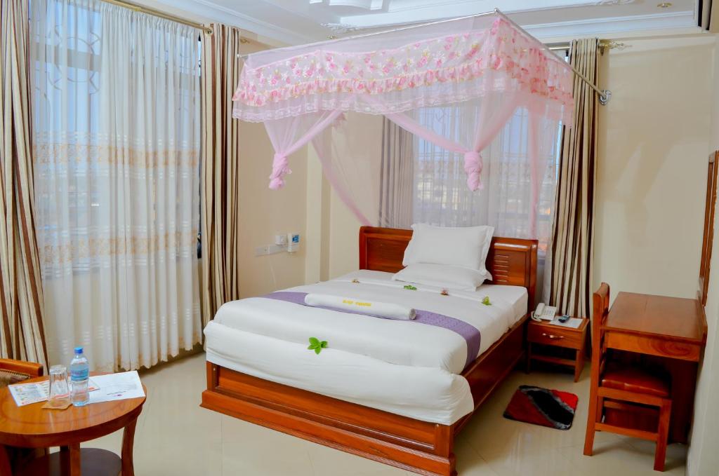 1 dormitorio con 1 cama con dosel rosa en Silver Paradise Hotel en Dar es Salaam