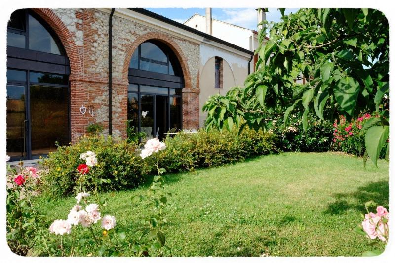 a brick building with a yard with pink flowers at Corte delle Giuggiole in Cologna Veneta