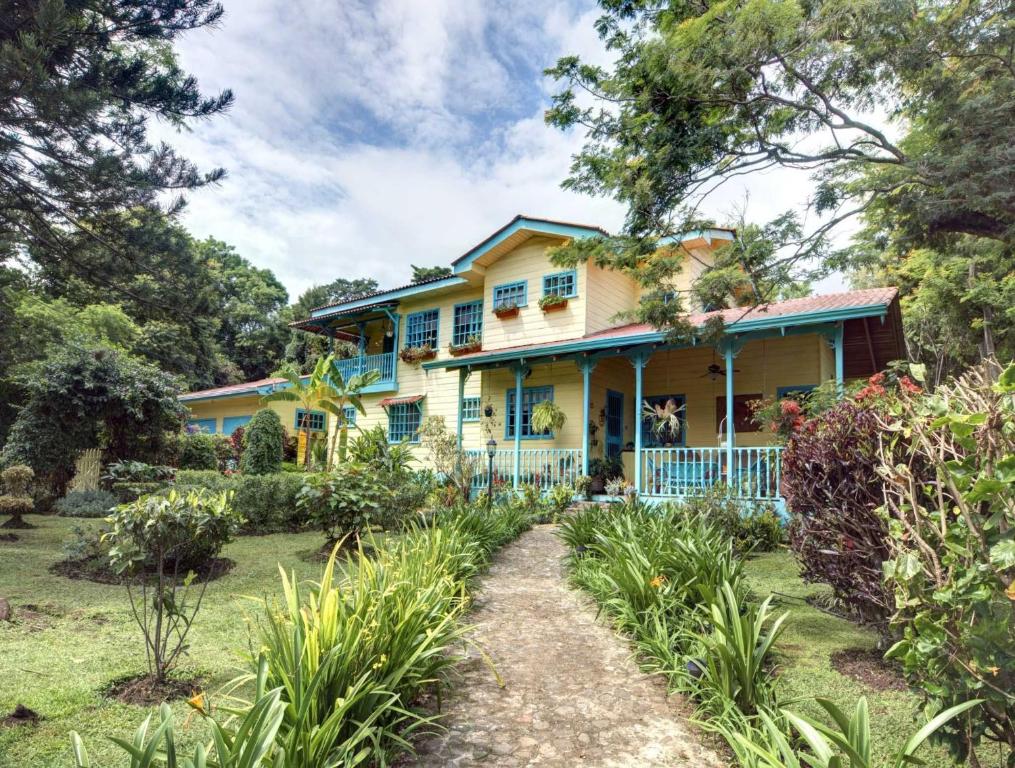 żółty dom z niebieskimi okiennicami i ogródkiem w obiekcie Casa De Las Tias w San José