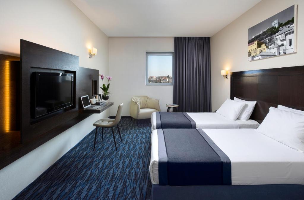 ein Hotelzimmer mit 2 Betten und einem Flachbild-TV in der Unterkunft Golden Crown Old City Hotel in Nazareth