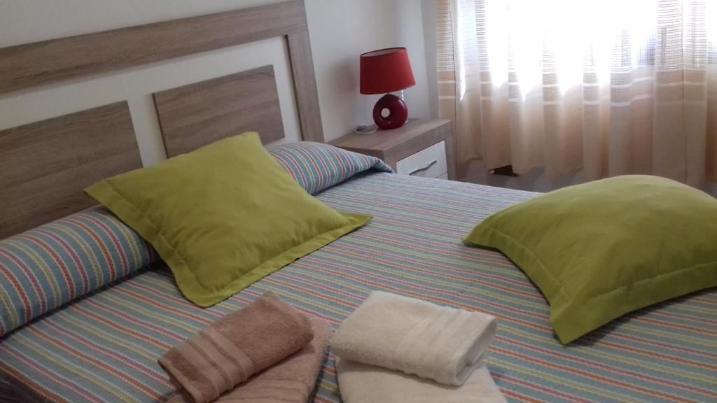 Una cama con dos almohadas verdes encima. en Casa Yaya Felisa, en Lledó