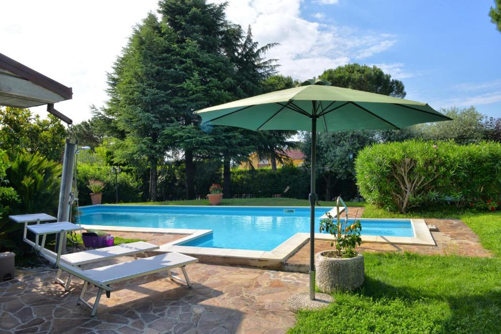 a green umbrella sitting next to a swimming pool at Casa Maria in Manerba del Garda