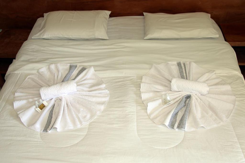uma cama branca com duas toalhas em cima em Pousada Solar dos Guaras em Catas Altas