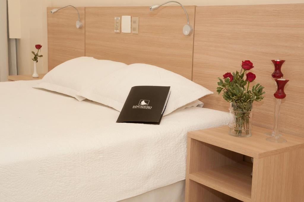 a laptop on a bed with flowers on a table at Hotel Jangadeiro in Recife