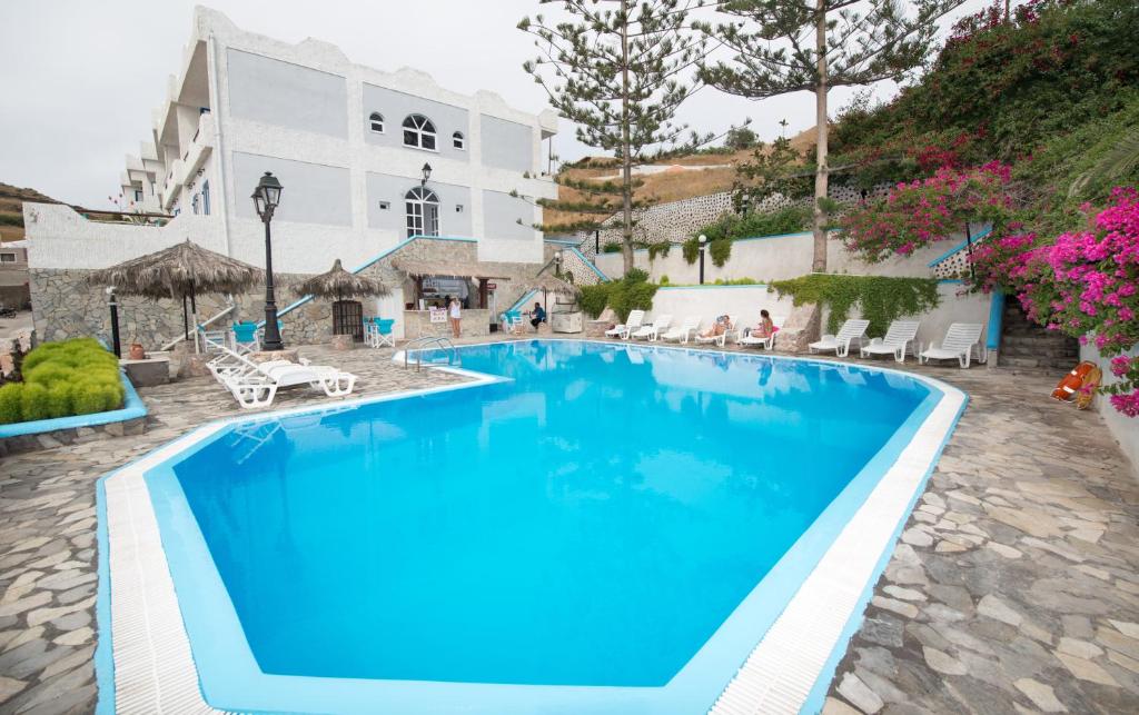 
a swimming pool with a blue and white pool table and chairs at Porto Castello in Fira
