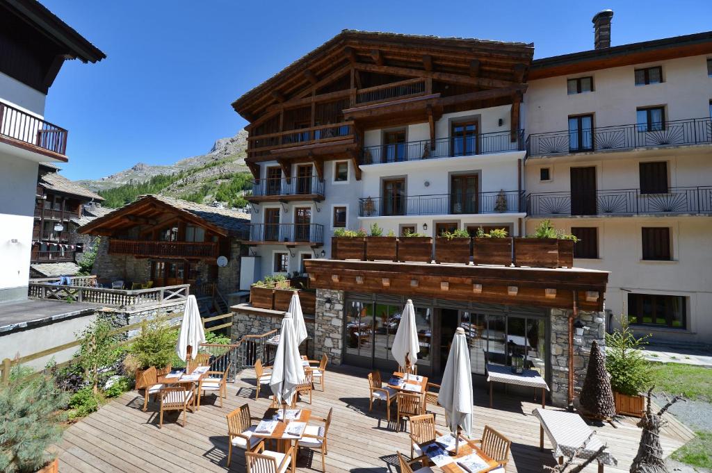 a hotel with a deck with chairs and umbrellas at Maison de Famille Les 5 Frères in Val dʼIsère