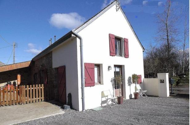 a white house with red windows and a fence at Gîte Carpe Diem in Quimperlé