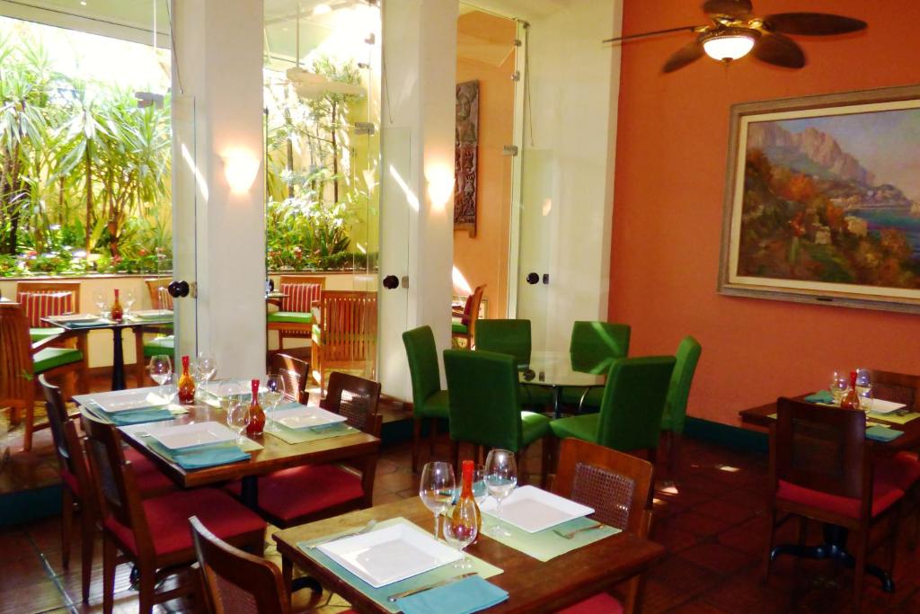 a restaurant with wooden tables and green chairs at Hotel Casa do Amarelindo in Salvador