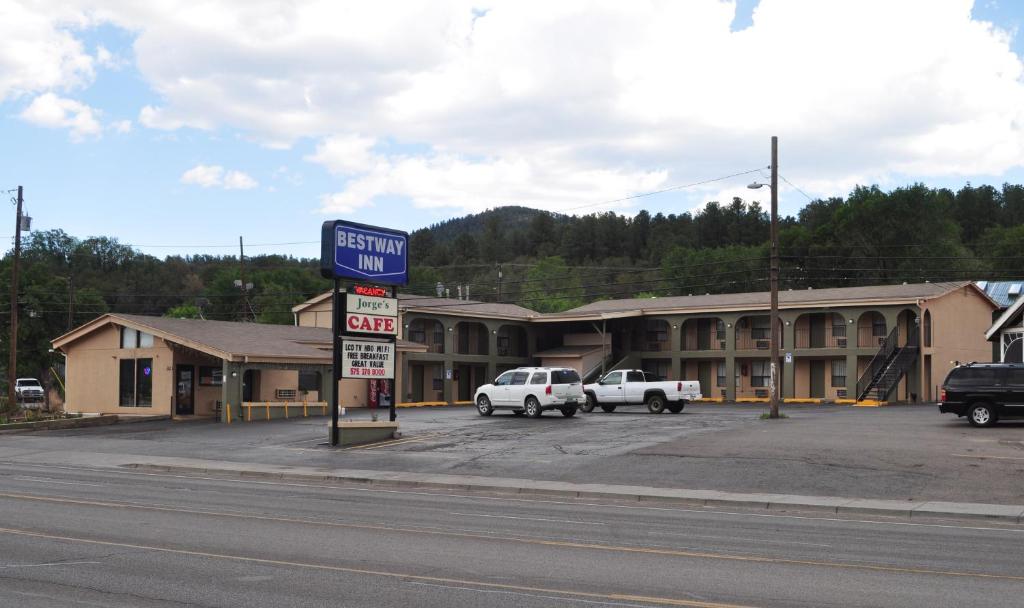 a sign for a hotel with cars parked in a parking lot at Bestway Inn in Ruidoso Downs