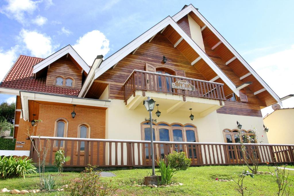 a house with a wooden roof and a balcony at Pousada Recanto Paulista in Campos do Jordão