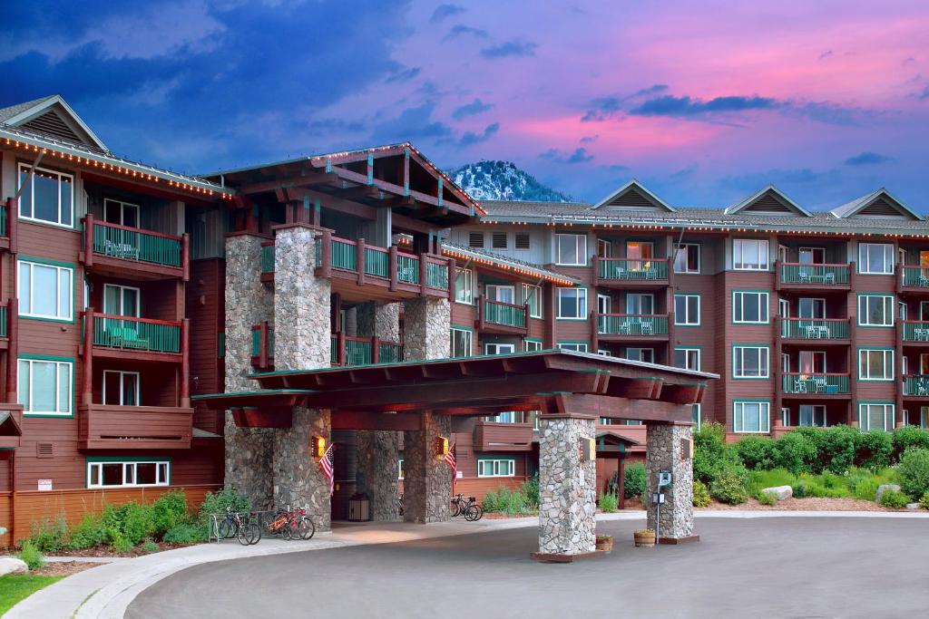 a large apartment building with a sunset in the background at Juniper Springs Resort in Mammoth Lakes