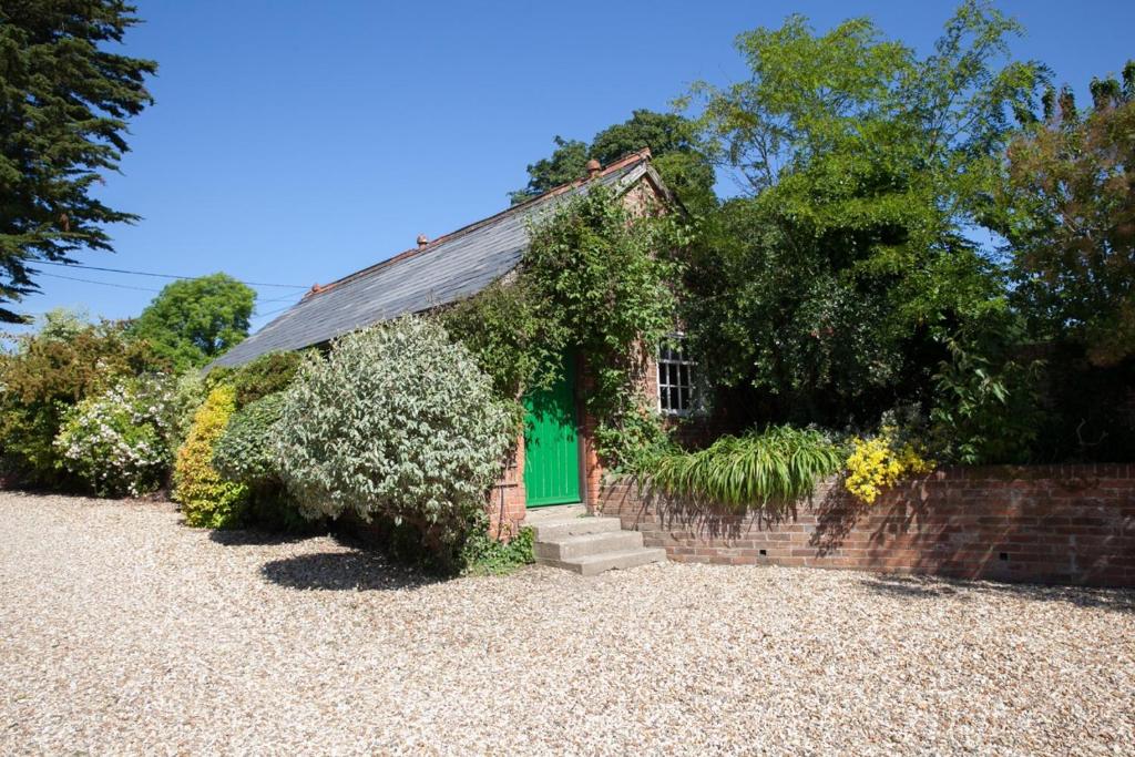 ein kleines Backsteinhaus mit grüner Tür in der Unterkunft Bramble Cottage in Whiteparish