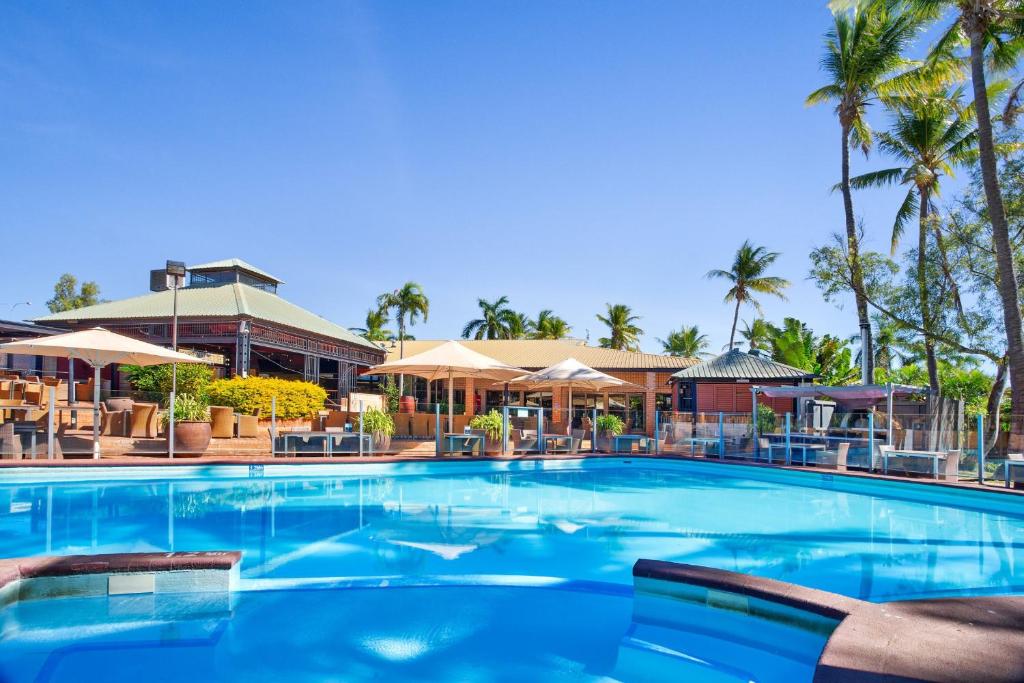 a large pool with chairs and umbrellas at a resort at Karratha International Hotel in Karratha