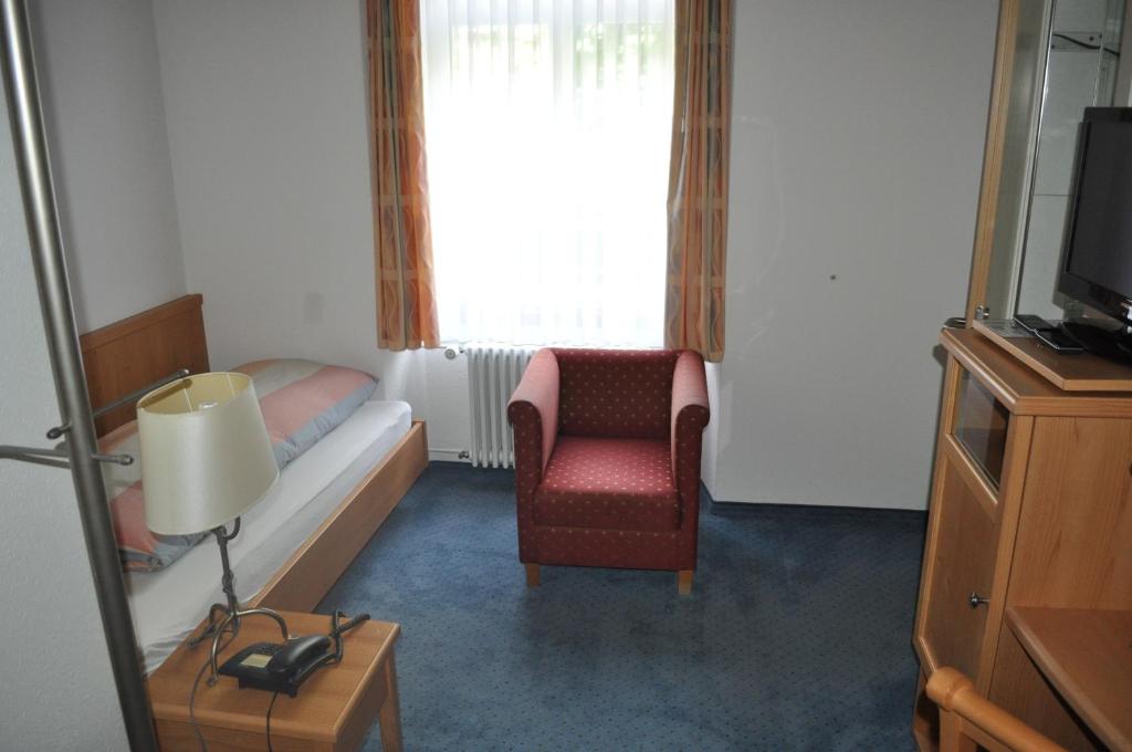 a room with a bed and a chair and a television at Hotel Engelberg "mein Trail Hotel" in Engelberg