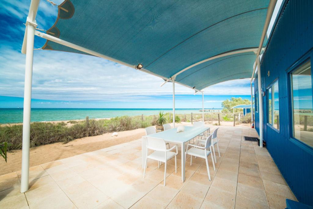 um pátio com uma mesa e cadeiras e o oceano em Mackerel Islands em Onslow